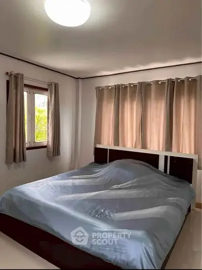 Cozy bedroom with large window and elegant curtains, perfect for relaxation and comfort.