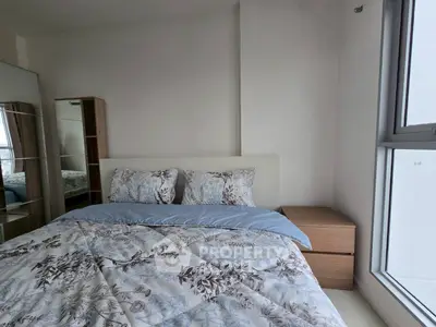 Cozy bedroom with floral bedding and natural light from large window