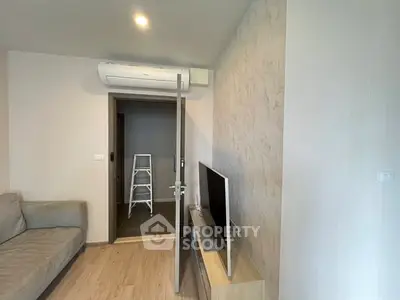 Modern living room with air conditioning and TV, featuring a cozy sofa and wooden flooring.