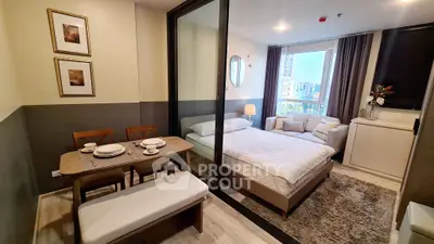 Modern studio apartment with cozy bedroom and dining area, featuring large windows and stylish decor.