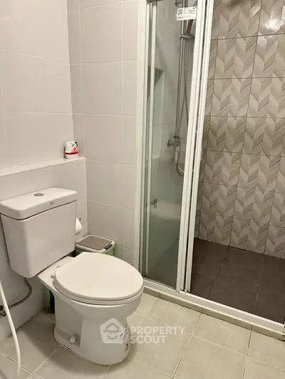 Modern bathroom with sleek shower and toilet in contemporary apartment.