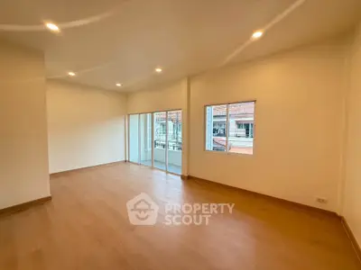 Spacious empty living room with wooden flooring and large windows