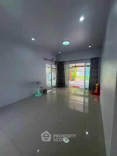 Spacious living room with large windows and tiled flooring, offering a bright and airy atmosphere.