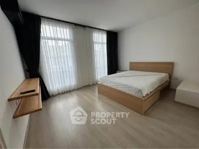 Spacious bedroom with modern minimalist design and large windows for natural light.