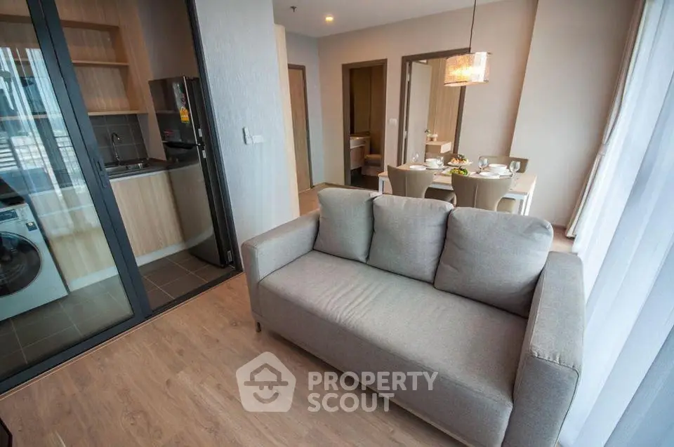 Modern open-plan living room with cozy sofa and dining area in stylish apartment.