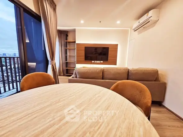 Modern living room with city view, featuring cozy sofa and stylish dining area.