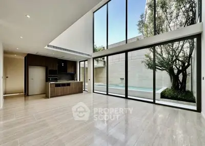 Spacious modern living room with floor-to-ceiling windows and pool view.