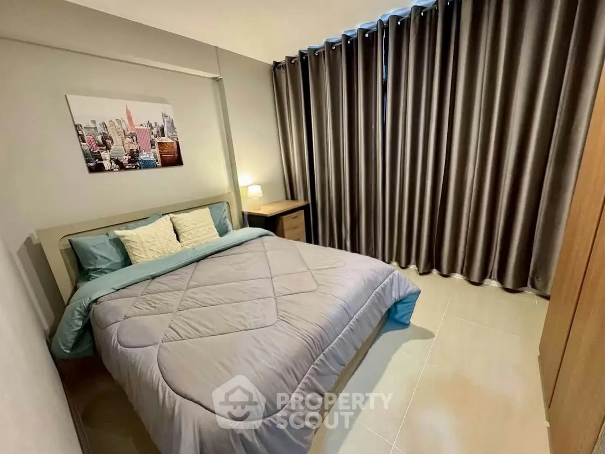 Cozy bedroom with modern decor and large window draped with elegant curtains, perfect for relaxation.