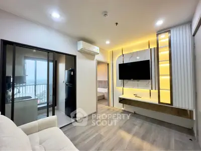 Modern living room with sleek design, featuring a wall-mounted TV and ambient lighting, adjacent to a compact kitchen.