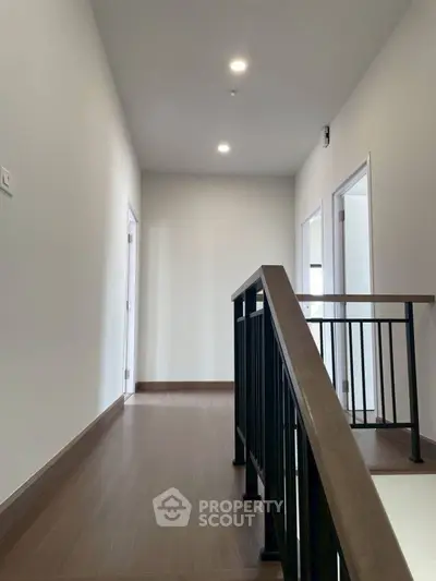 Modern hallway with sleek wooden flooring and contemporary railing design.