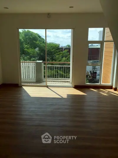 Spacious living room with large windows and balcony access, offering abundant natural light and scenic views.