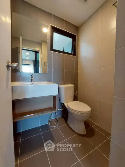 Modern bathroom with sleek design and neutral tiles, featuring a compact layout.