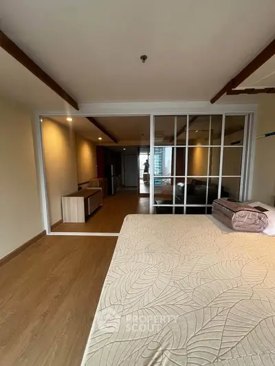 Spacious modern bedroom with sliding glass doors and wooden flooring in a stylish apartment.