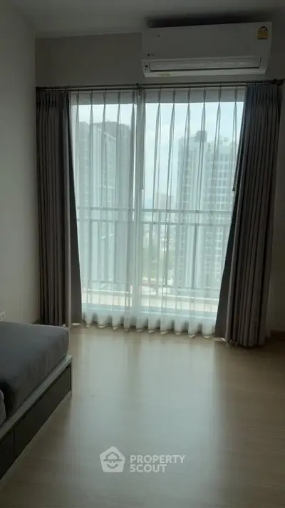 Modern bedroom with large window offering city view and natural light.