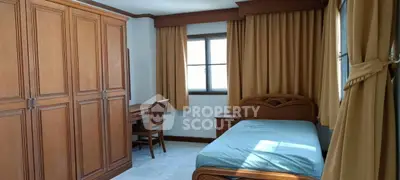 Spacious bedroom with wooden furniture and large windows for natural light.