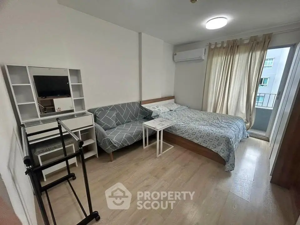 Cozy bedroom with modern decor, featuring a bed, sofa, and balcony access for urban living.
