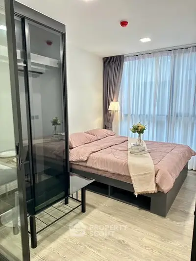 Modern bedroom with large window and stylish decor in a cozy apartment.