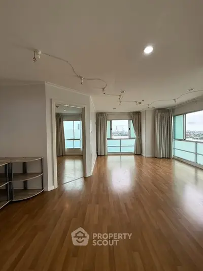 Spacious living room with wooden flooring and large windows offering stunning views.