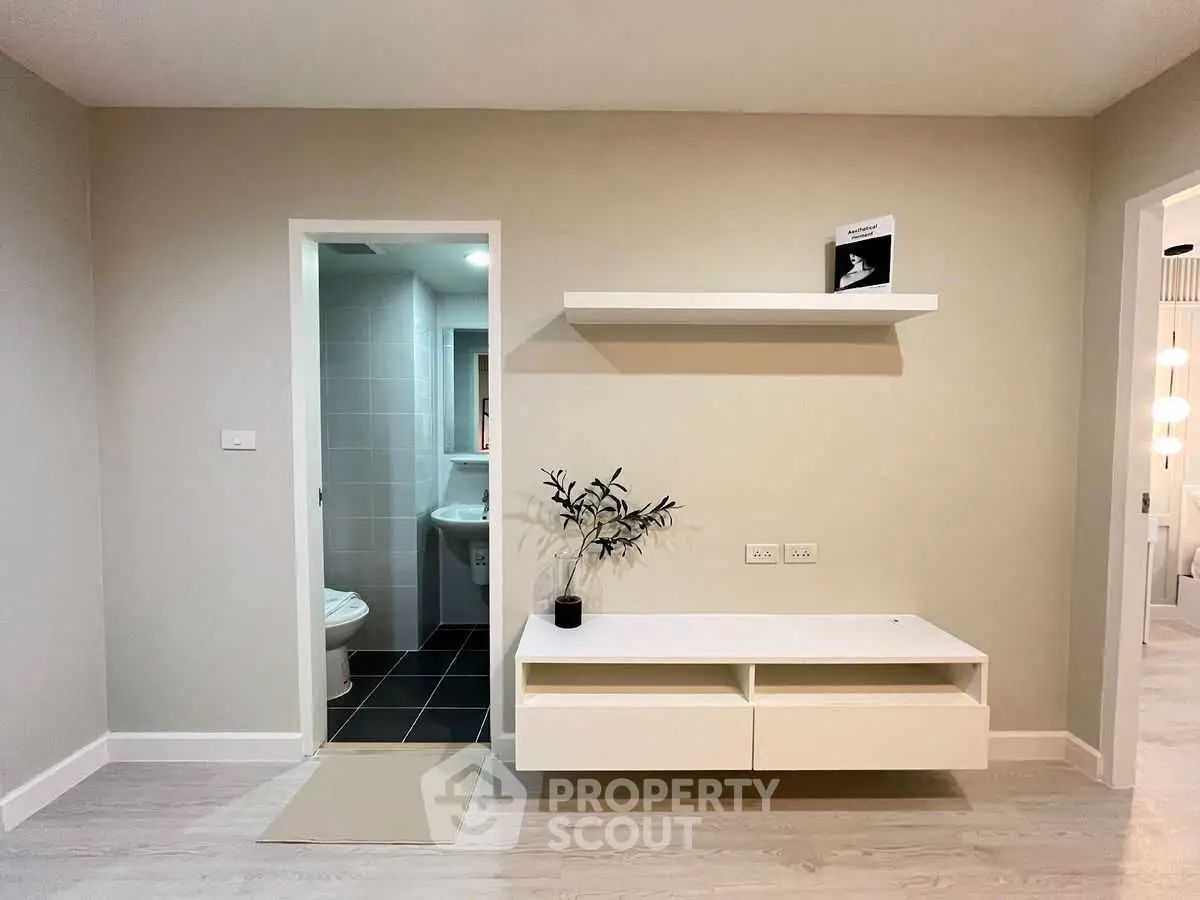 Modern minimalist interior with sleek white furniture and open bathroom view.