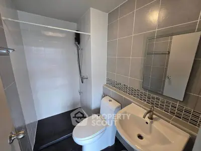 Modern bathroom with sleek tiles and walk-in shower in contemporary apartment.