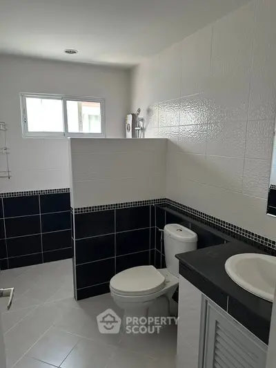 Modern bathroom with sleek black and white tiles and natural light.