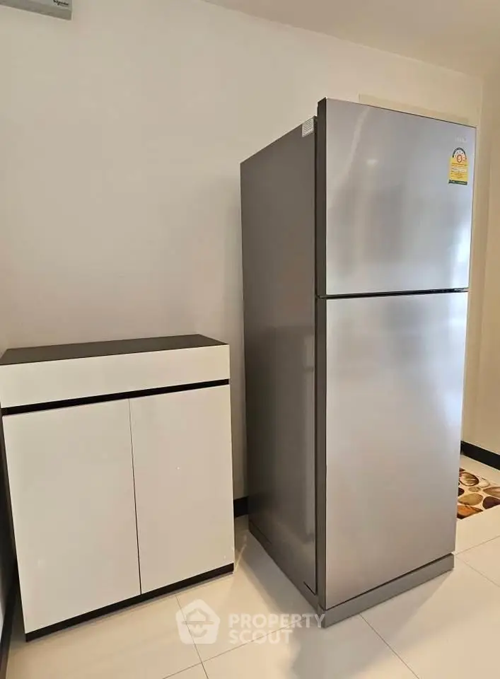 Modern kitchen with sleek fridge and stylish cabinet in a contemporary apartment.