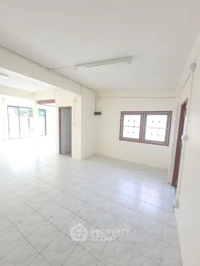 Spacious and bright living room with tiled flooring and large windows.