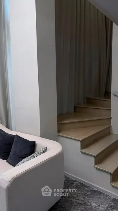 Modern interior with stylish staircase and cozy seating area, perfect for contemporary living.