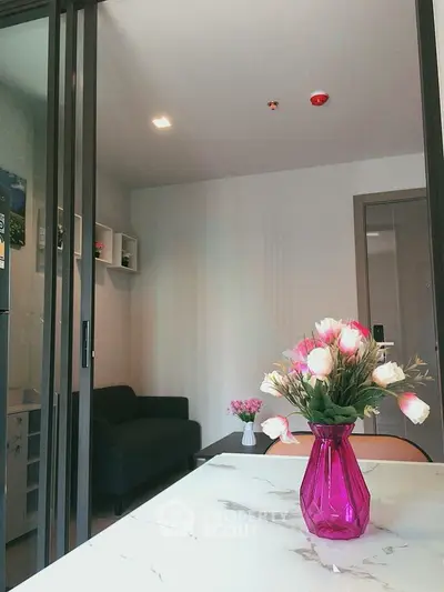 Modern living room with stylish decor and vibrant pink vase on marble table.