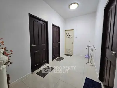 Spacious hallway with elegant dark wood doors and glossy tiled flooring