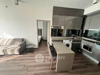 Modern open-plan living room with sleek kitchen and cozy bedroom view.