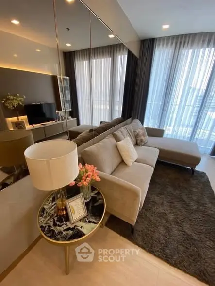 Modern living room with plush sofa and elegant decor, featuring floor-to-ceiling windows and a cozy ambiance.