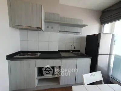 Modern kitchen with sleek cabinets, electric stove, and spacious fridge in a cozy apartment.