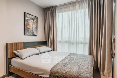 Cozy bedroom with modern decor and large window for natural light.