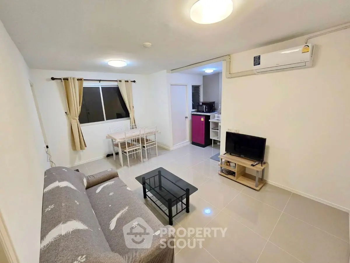 Cozy living room with modern furniture and open kitchen layout in a bright apartment.