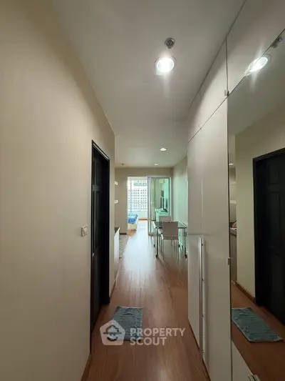 Modern apartment hallway leading to a bright living area with wooden flooring and stylish decor.