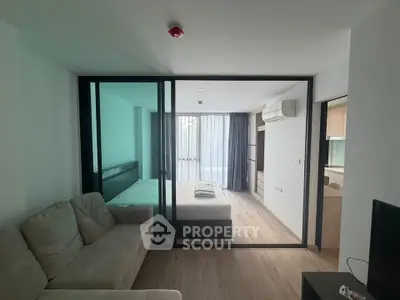 Modern studio apartment with glass partition, cozy sofa, and natural light.