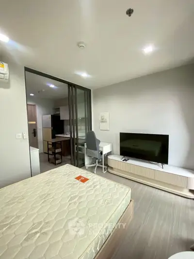 Modern studio apartment with open layout, featuring a cozy bedroom and compact kitchen area.