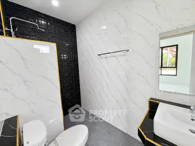 Modern bathroom with elegant black and white tiles, featuring a sleek shower and stylish sink.