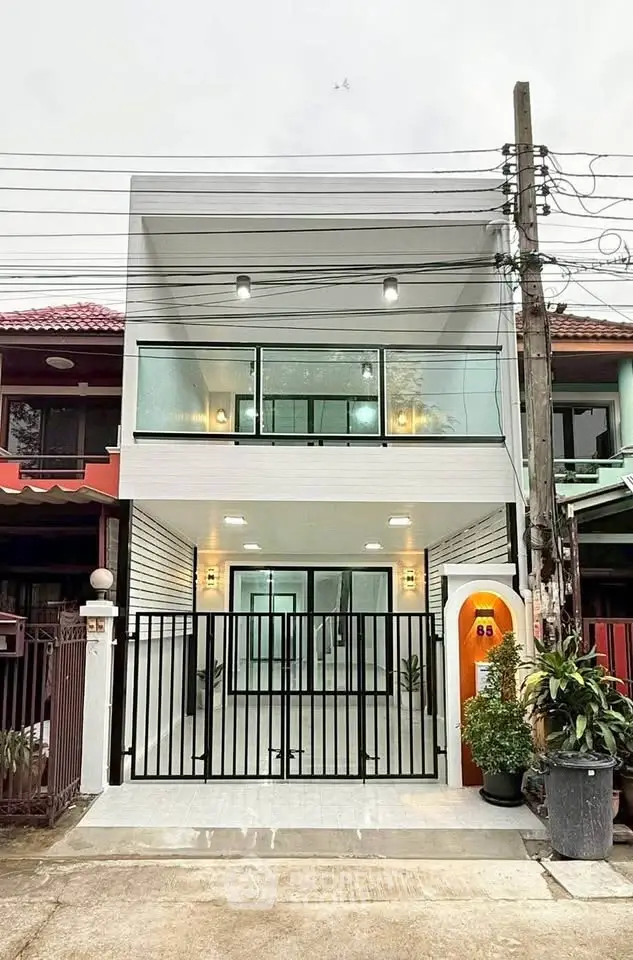 Modern townhouse exterior with sleek glass facade and gated entrance in urban setting.