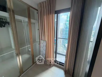 Modern bedroom with floor-to-ceiling windows and city view, featuring a spacious wardrobe and elegant curtains.