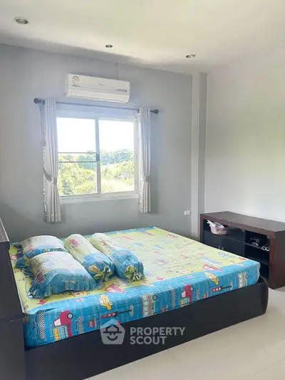 Bright bedroom with a scenic view, featuring modern air conditioning and colorful bedding.