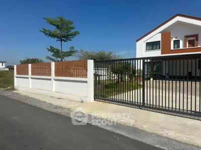Modern suburban house with gated driveway and lush greenery
