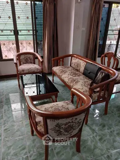Charming living room with vintage wooden furniture and large windows for natural light.