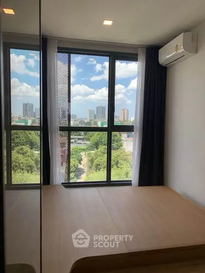 Modern bedroom with large window offering stunning city and greenery views, featuring sleek air conditioning unit.
