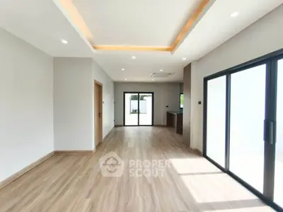Spacious modern living room with wooden flooring and large sliding glass doors.