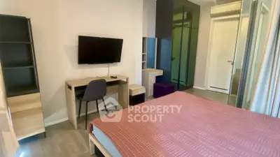 Modern bedroom with TV, desk, and stylish decor in a cozy apartment.