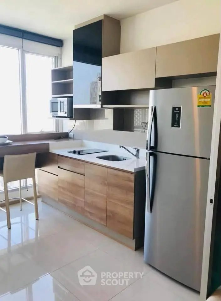 Modern kitchen with sleek cabinetry and stainless steel appliances in a bright apartment.