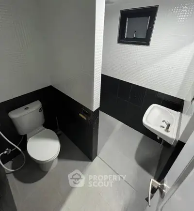 Modern minimalist bathroom with sleek black and white tiles and compact fixtures.