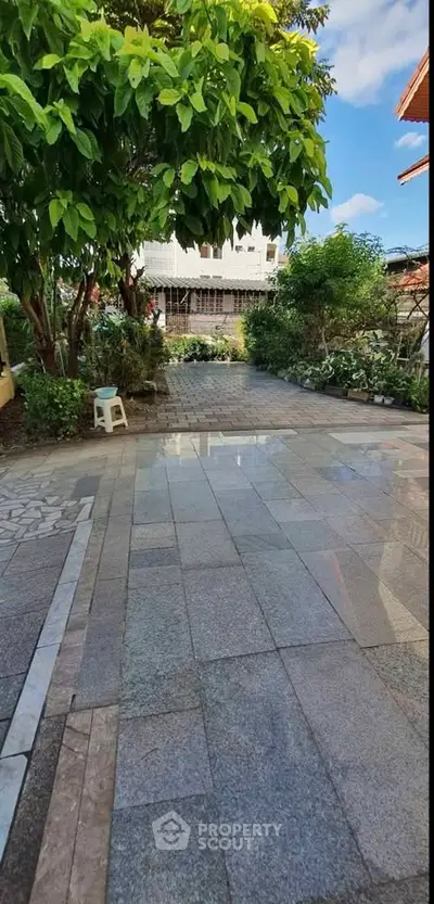 Spacious outdoor garden area with lush greenery and paved walkway, perfect for relaxation and outdoor activities.